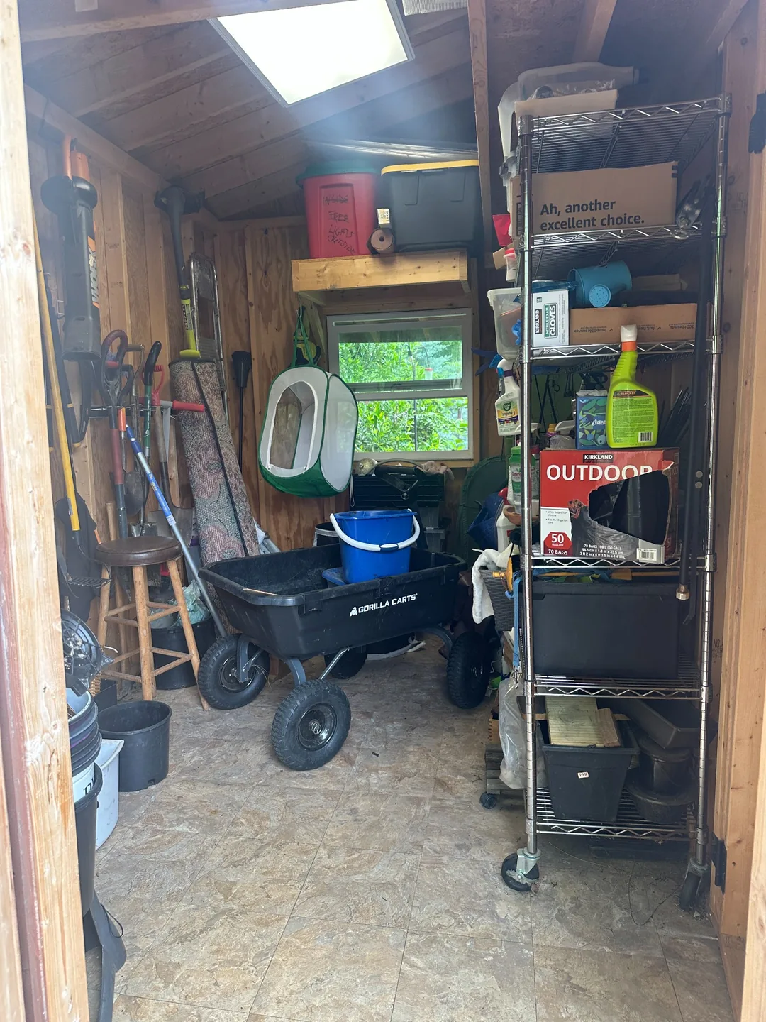 Garden shed before organizing, with a wagon and other items in the central aisle.